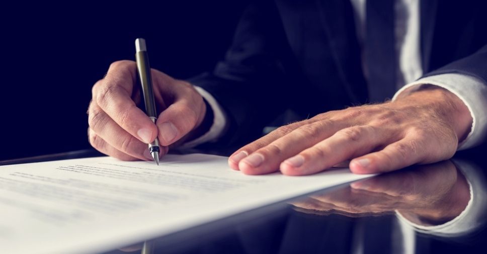 Profissional assina documento físico para exemplificar o controle DJE e processos jurídicos.